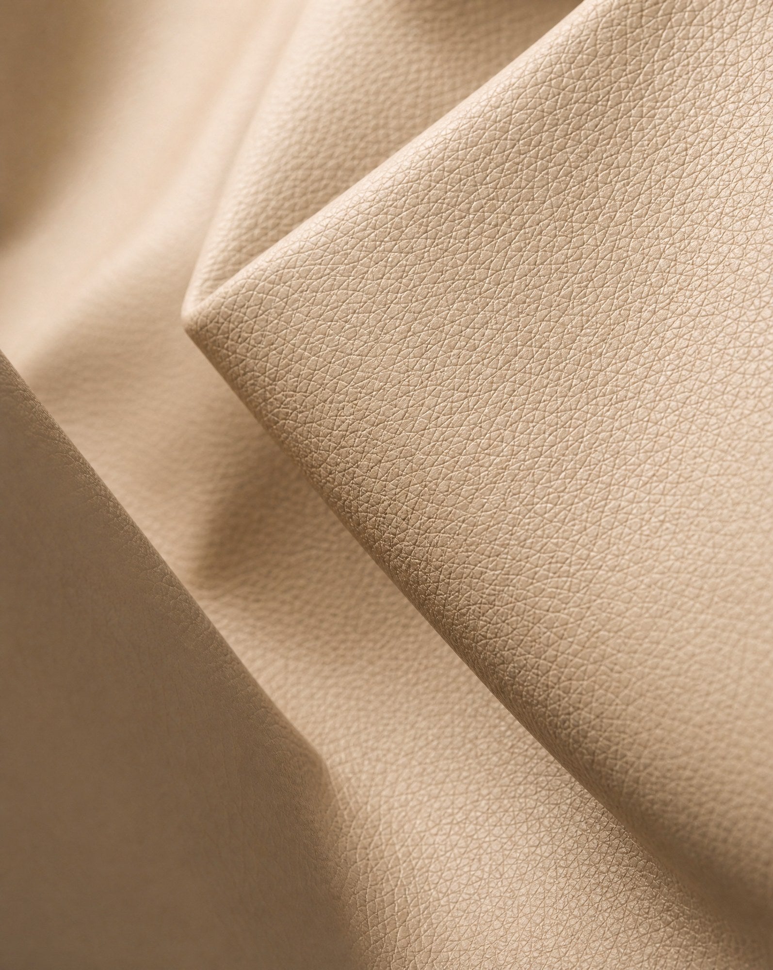 Macro detail of the pebbled vegan leather, folded so the light catches the grain